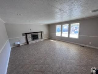 unfurnished living room with baseboards, a textured ceiling, visible vents, and a fireplace