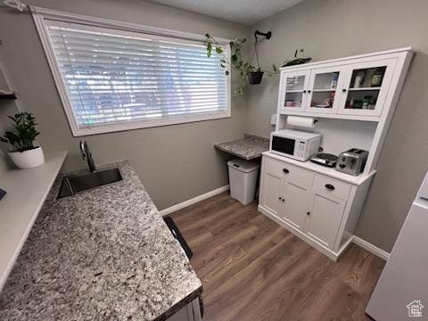 kitchen featuring white cabinets, wood finished floors, white microwave, and a sink