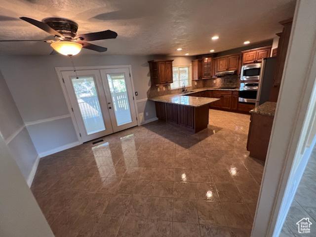 kitchen featuring light tile patterned flooring, ceiling fan, french doors, a peninsula, and appliances with stainless steel finishes