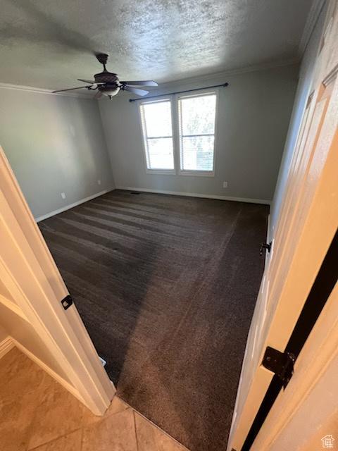 unfurnished bedroom featuring carpet floors, ornamental molding, a textured ceiling, and baseboards