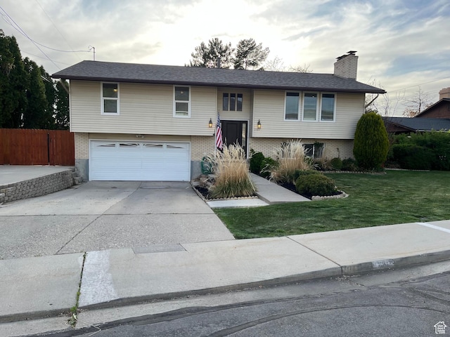 bi-level home featuring brick siding, an attached garage, and driveway