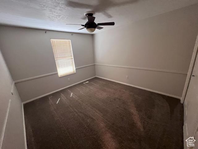 unfurnished room featuring a ceiling fan, baseboards, and dark colored carpet