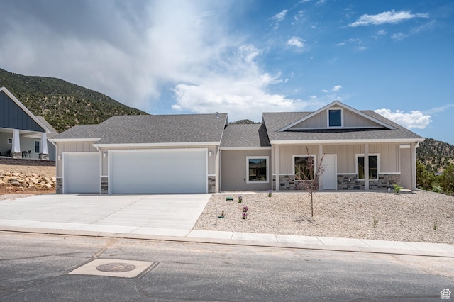 1152 E Smokey Trail Way, Cedar City, UT 84721 - view of front facade with stone siding, an attached garage, driveway, a shingled roof, and a mountain view