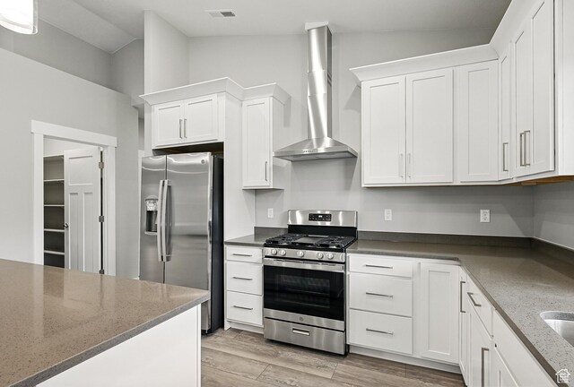 1152 E Smokey Trail Way, Cedar City, UT 84721 - kitchen featuring stainless steel appliances, wall chimney range hood, white cabinets, light wood-style floors, and dark stone counters