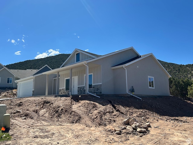 1152 E Smokey Trail Way, Cedar City, UT 84721 - view of front facade with a garage, board and batten siding, covered porch, stone siding, and a mountain view