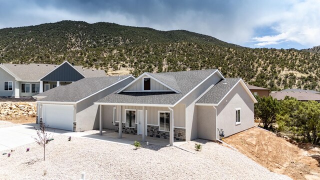 1152 E Smokey Trail Way, Cedar City, UT 84721 - view of front of home with driveway, a mountain view, stone siding, a shingled roof, and a garage