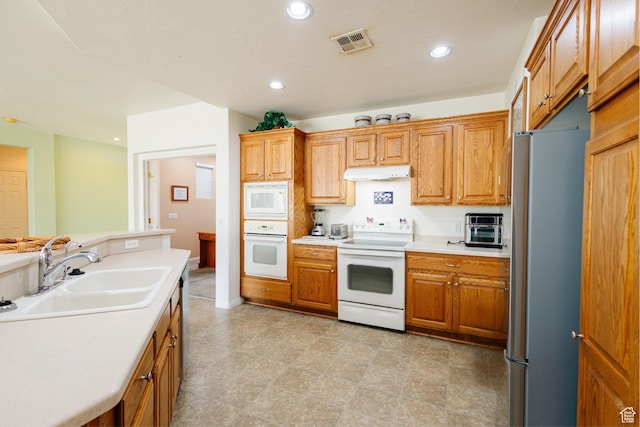 kitchen featuring a sink, visible vents, white appliances, light countertops, and under cabinet range hood