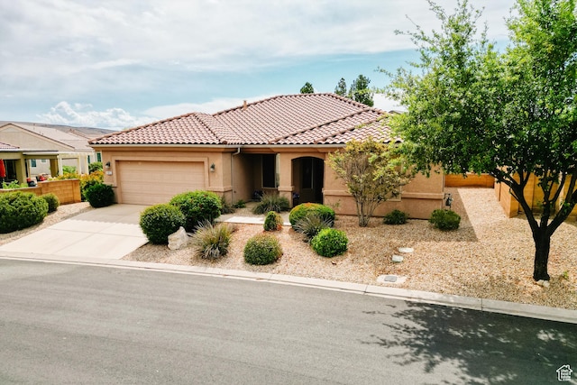 view of front of home with stucco siding, a tile roof, concrete driveway, and a garage