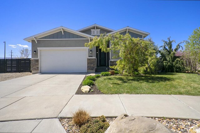 6961 W Goblin Valley Cv S, West Jordan, UT 84081 - craftsman-style house featuring a front lawn, stone siding, concrete driveway, fence, and a garage