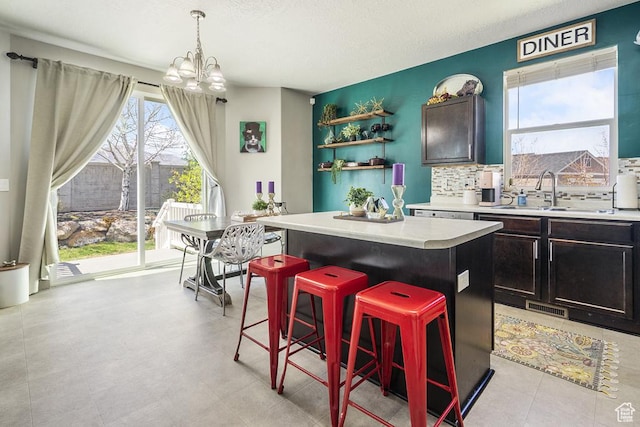 6961 W Goblin Valley Cv S, West Jordan, UT 84081 - kitchen with a center island, a sink, visible vents, a notable chandelier, and a kitchen bar