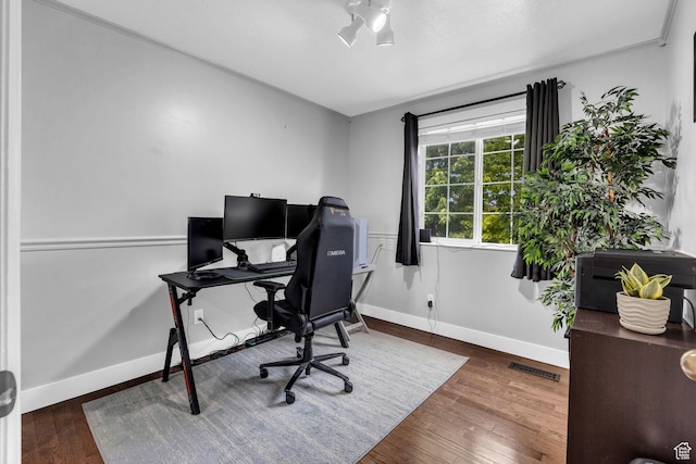 office space featuring wood finished floors, visible vents, baseboards, and ornamental molding
