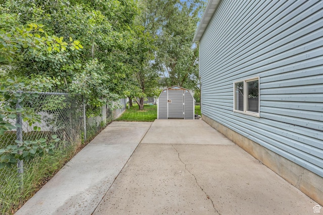 view of patio / terrace with a fenced backyard, a storage unit, and an outbuilding