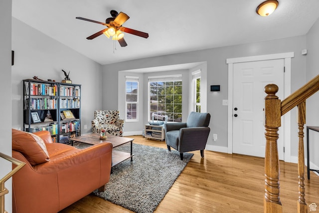 living area featuring ceiling fan, baseboards, stairs, and light wood-style flooring