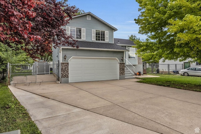 split level home featuring a gate, a garage, concrete driveway, fence, and a front yard