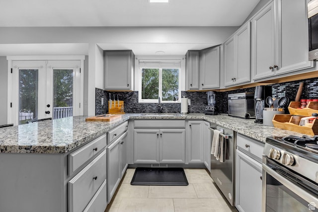 kitchen featuring a peninsula, stainless steel appliances, gray cabinetry, and a sink