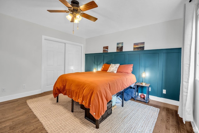 bedroom with ceiling fan, baseboards, wood finished floors, and a closet