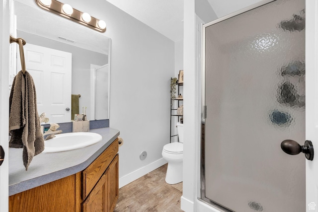 full bathroom with wood finished floors, visible vents, toilet, vanity, and a stall shower
