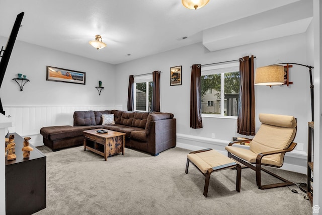 carpeted living area with visible vents and a wainscoted wall