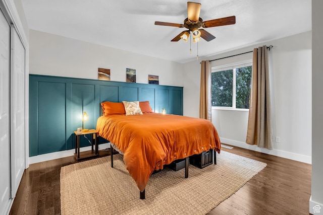 bedroom featuring dark wood finished floors, a ceiling fan, and a wainscoted wall