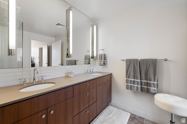 bathroom featuring baseboards, a sink, visible vents, and double vanity