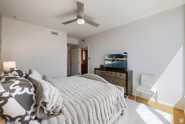 bedroom with light wood-style flooring, visible vents, baseboards, and ceiling fan