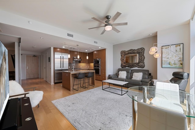 living room with light wood finished floors, a ceiling fan, visible vents, and recessed lighting