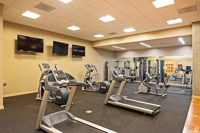 exercise room with a paneled ceiling and baseboards