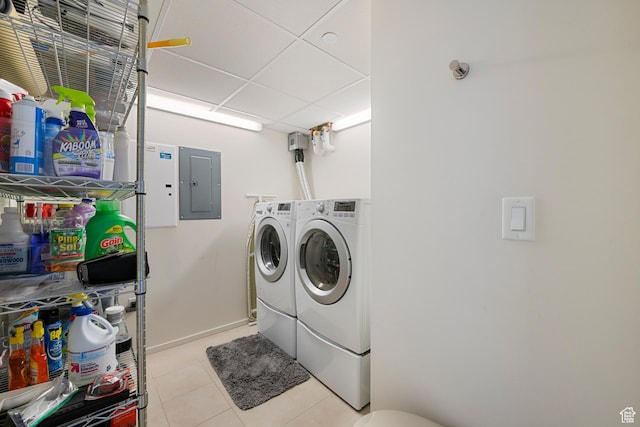 clothes washing area featuring electric panel, baseboards, washer and dryer, laundry area, and light tile patterned floors