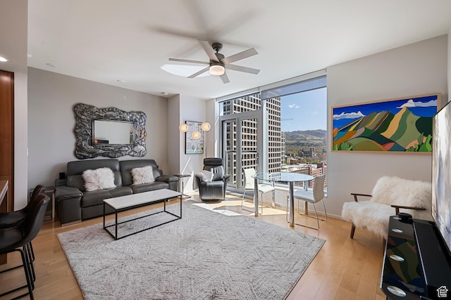 living area with wood finished floors, a ceiling fan, and floor to ceiling windows