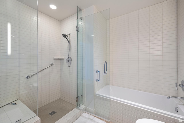 bathroom with a shower stall and a relaxing tiled tub
