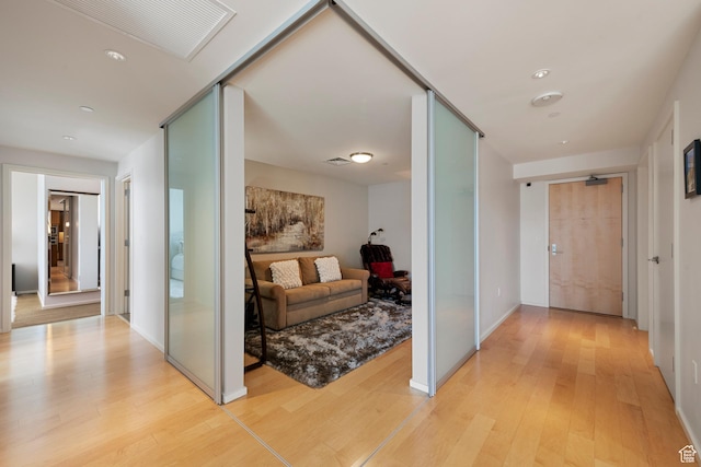 hallway with light wood-style floors and visible vents