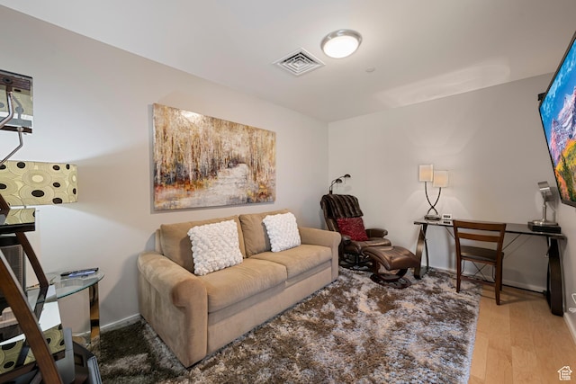 living area with baseboards, wood finished floors, and visible vents