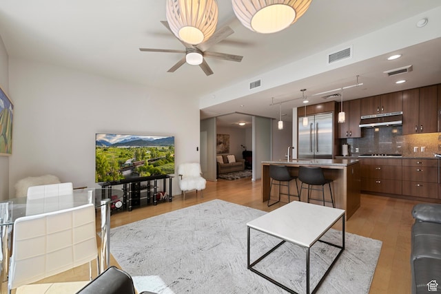 living area with light wood finished floors, visible vents, and a ceiling fan