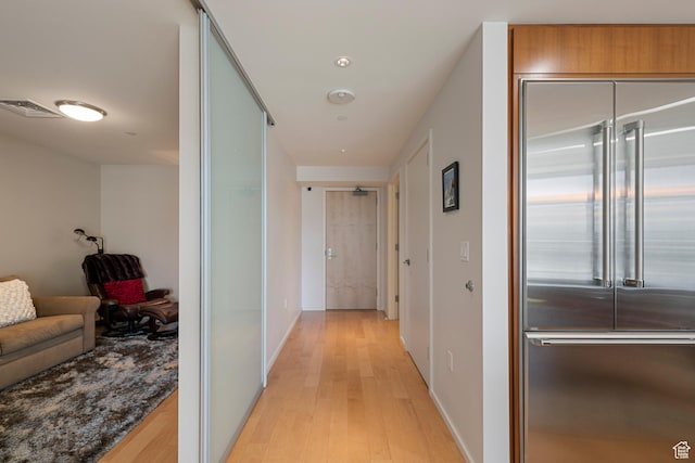 corridor with baseboards, visible vents, and light wood-type flooring