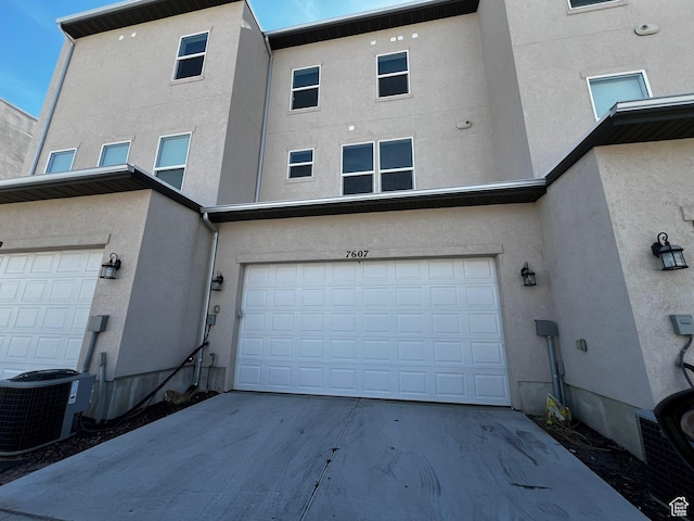 7607 S Bear Gulch Rd, West Jordan, UT 84081 - rear view of house with central air condition unit, driveway, a garage, and stucco siding