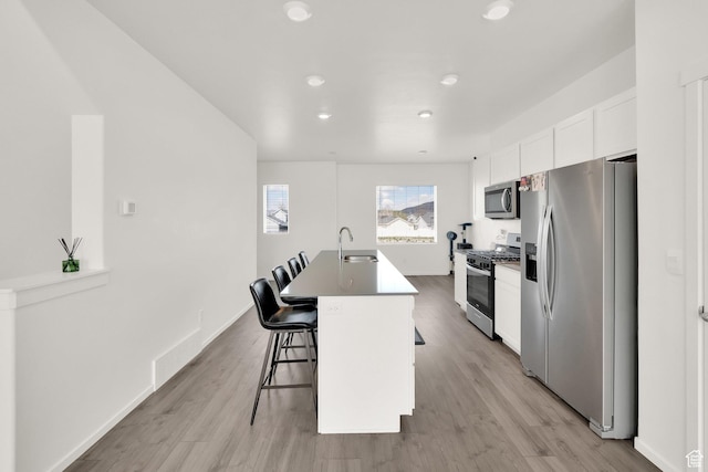 1751 E Wolverine Way, Eagle Mountain, UT 84005 - kitchen featuring stainless steel appliances, a kitchen island with sink, a sink, white cabinetry, and a breakfast bar