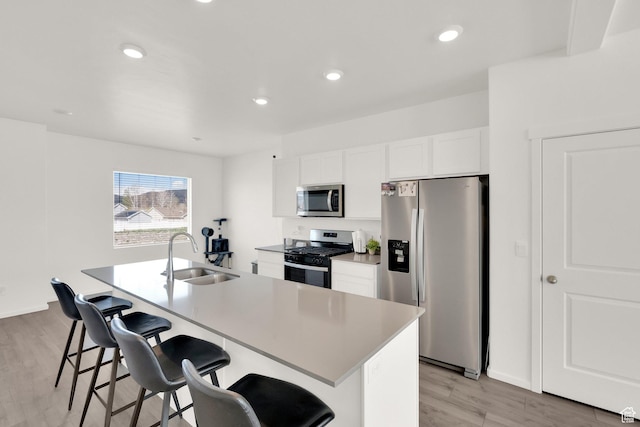 1751 E Wolverine Way, Eagle Mountain, UT 84005 - kitchen featuring a sink, light wood-style floors, stainless steel appliances, a center island with sink, and a kitchen bar