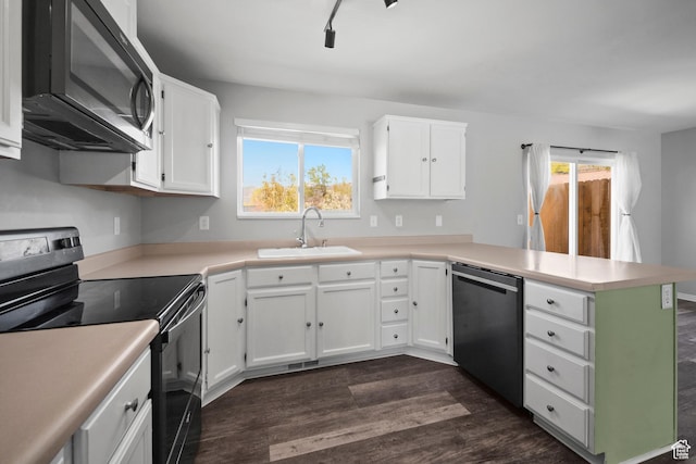 kitchen with dark wood finished floors, stainless steel dishwasher, range with electric cooktop, a sink, and a peninsula