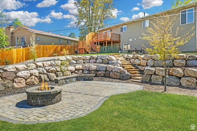 view of patio with stairway, fence, a wooden deck, and an outdoor fire pit