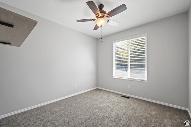 carpeted empty room featuring ceiling fan, visible vents, and baseboards