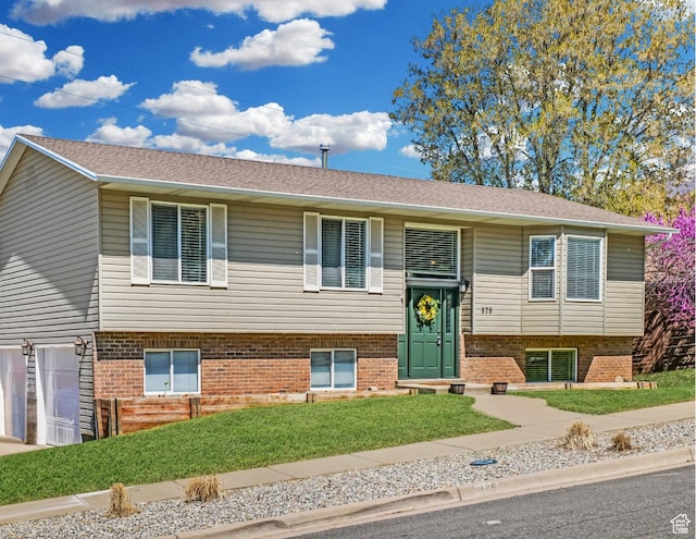 bi-level home with brick siding, a garage, and a front yard