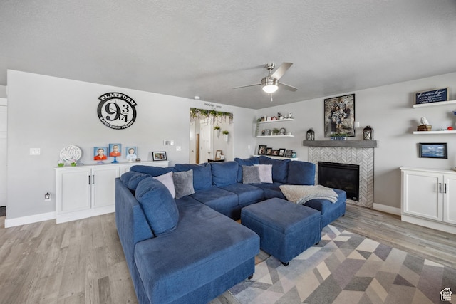 2448 W Anne Ave S, West Haven, UT 84401 - living room with light wood finished floors, a textured ceiling, a tiled fireplace, baseboards, and a ceiling fan