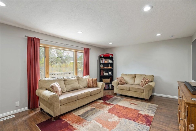 living area featuring a textured ceiling, baseboards, visible vents, recessed lighting, and wood finished floors
