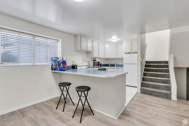 682 N 700 W, Provo, UT 84601 - kitchen with white appliances, light wood-type flooring, light countertops, a kitchen bar, and a peninsula