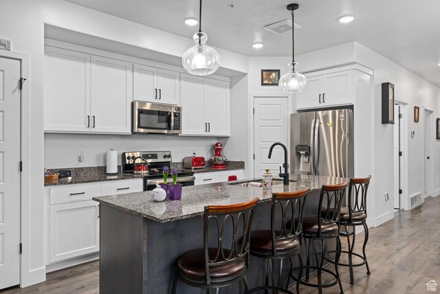 551 S 1020 W Unit 102, American Fork, UT 84003 - kitchen featuring wood finished floors, a sink, a breakfast bar, appliances with stainless steel finishes, and visible vents