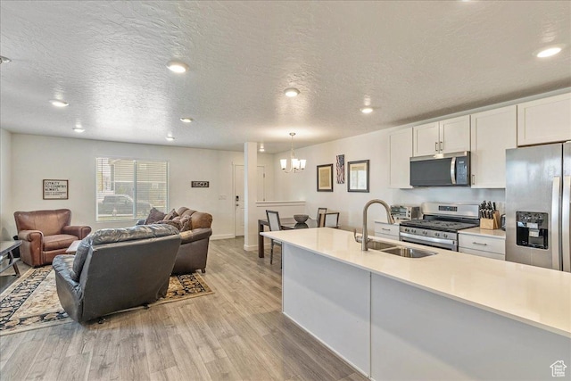 278 N Portside Ln, Saratoga Springs, UT 84045 - kitchen with a notable chandelier, a sink, open floor plan, light wood-style flooring, and appliances with stainless steel finishes