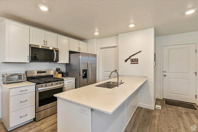 278 N Portside Ln, Saratoga Springs, UT 84045 - kitchen with a sink, stainless steel appliances, light wood finished floors, a peninsula, and white cabinetry
