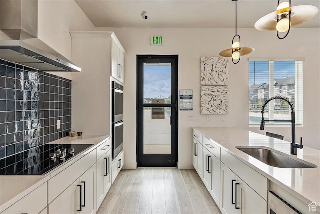 278 N Portside Ln, Saratoga Springs, UT 84045 - kitchen with black electric cooktop, wall chimney range hood, a sink, light wood-type flooring, and tasteful backsplash
