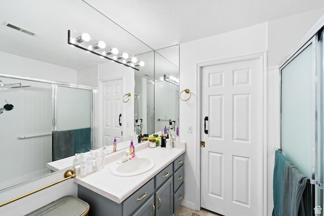 full bath featuring an enclosed shower, vanity, and visible vents