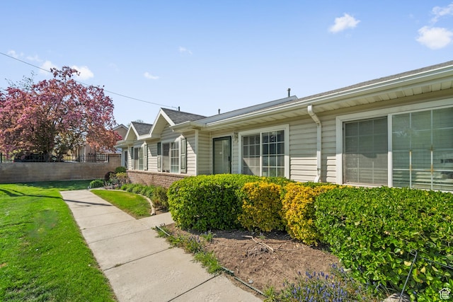 view of side of property featuring fence and a lawn